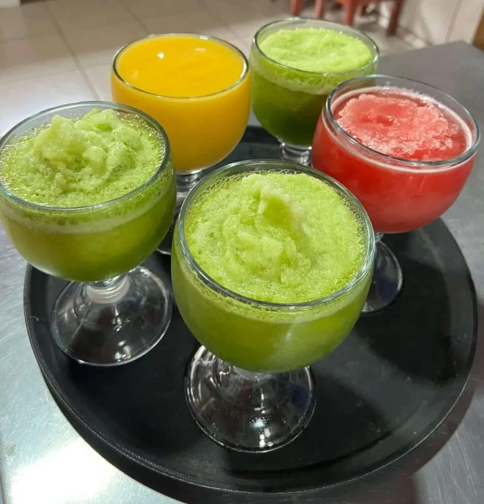 Vasos de batidos naturales de diferentes sabores servidos en copas sobre una bandeja