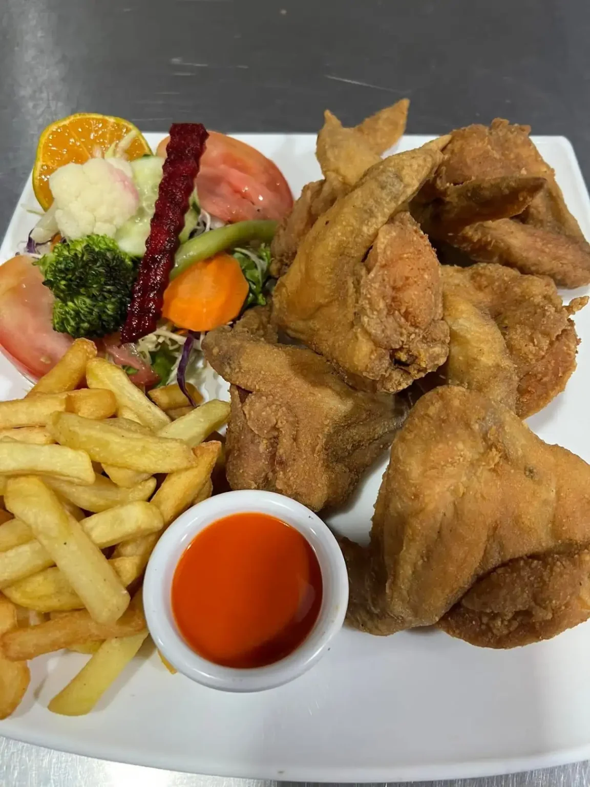 Alitas de pollo crujientes con papas y ensalada en Sol y Mar