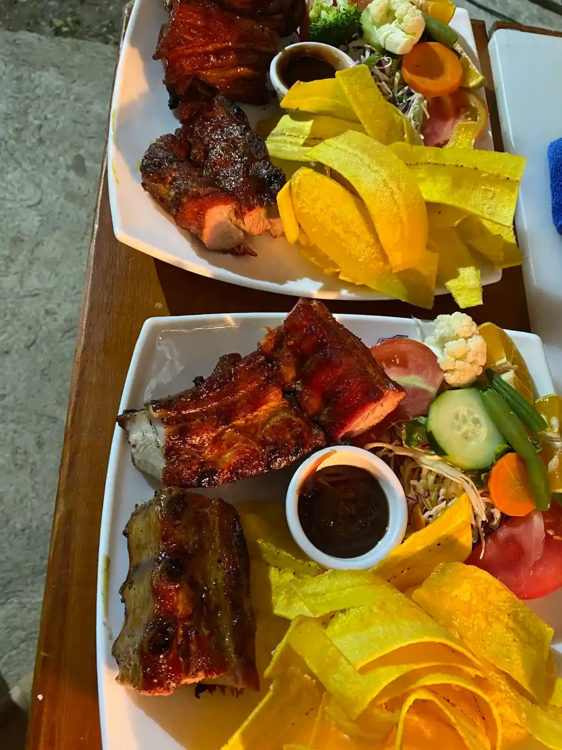 Costillas asadas servidas con patacones y ensalada fresca