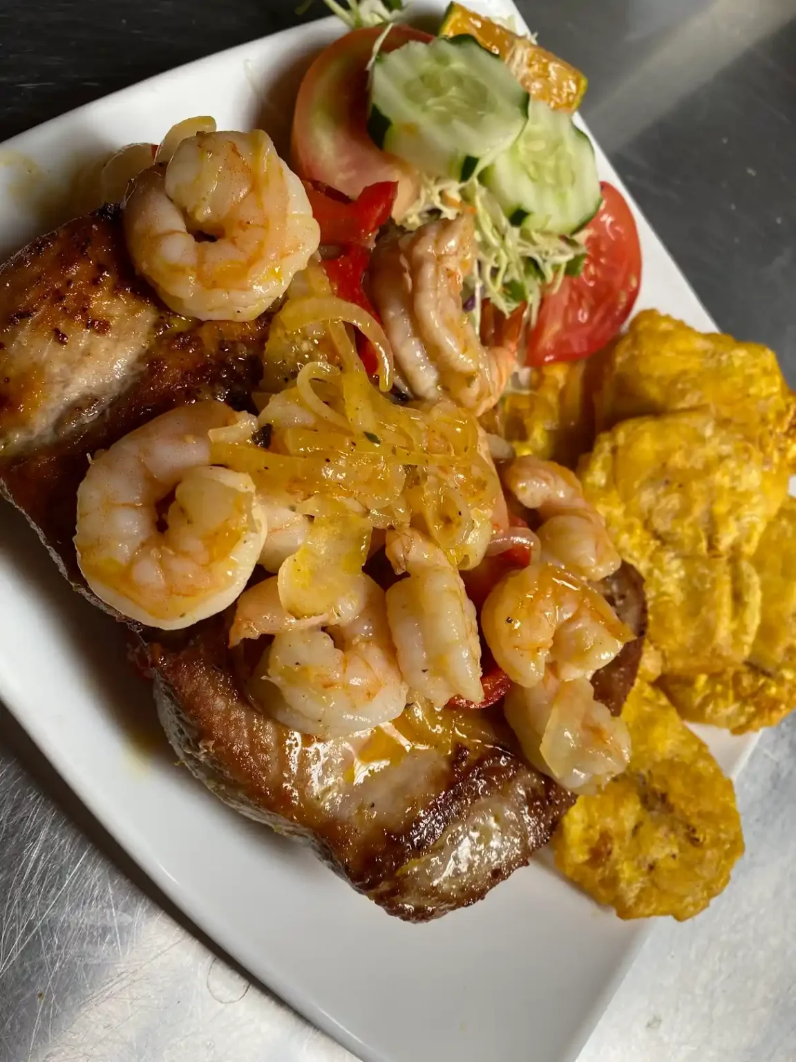 Filet de pescado cubierto con camarones y acompañado de patacones