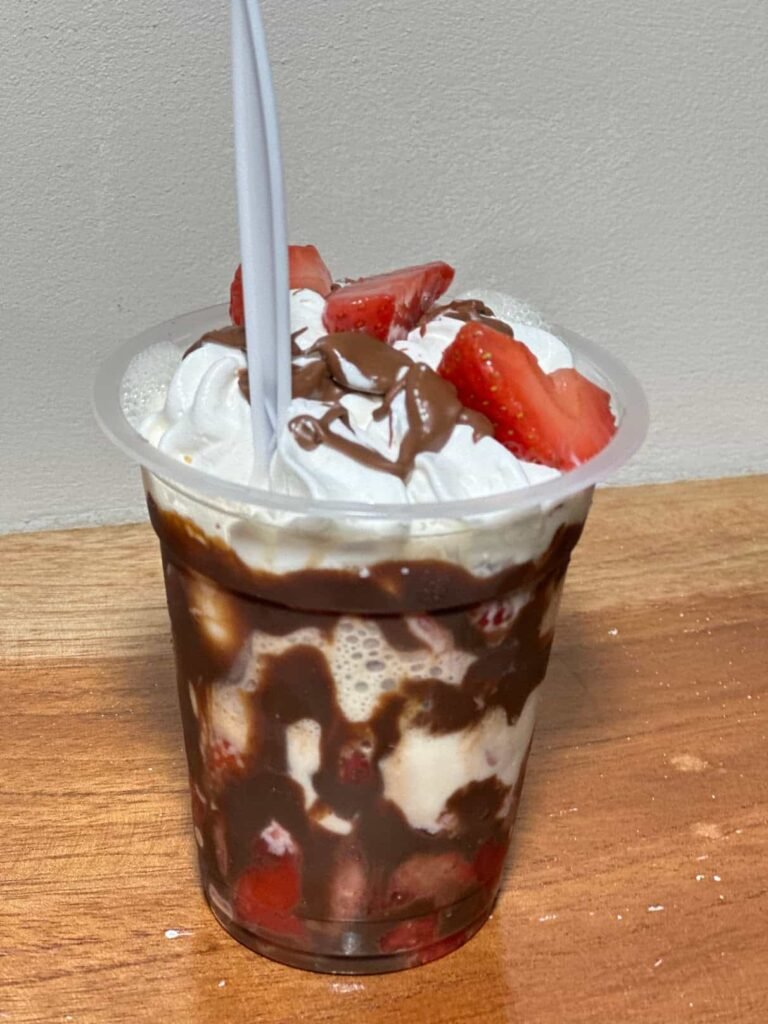 Vaso de fresas con crema batida y chocolate