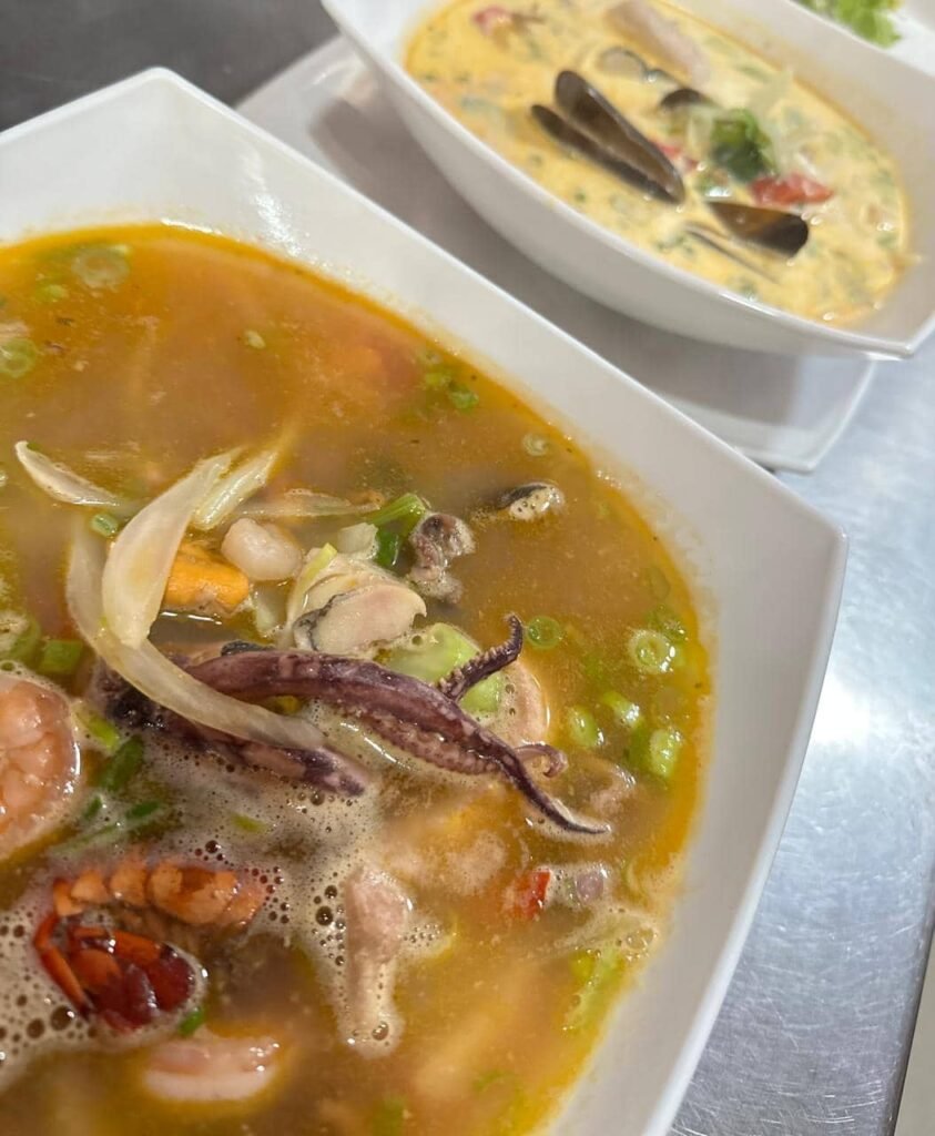 Platos hondos con sopas de mariscos servidas en tazones blancos