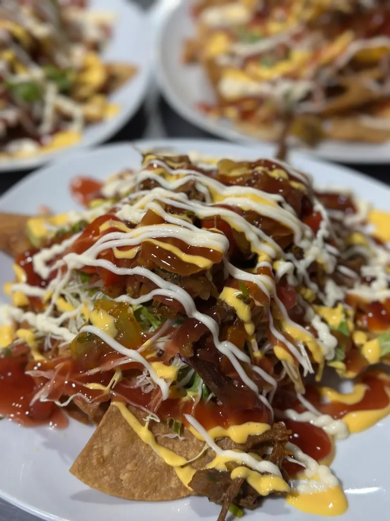 Nachos cubiertos con carne, queso y salsas
