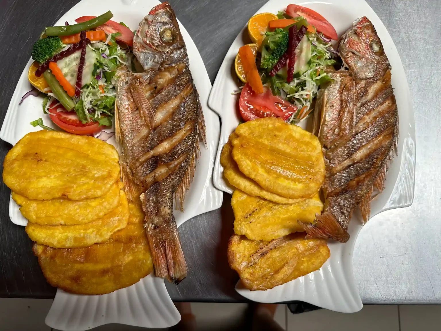 Pescado frito entero con patacones y ensalada, utilizado en el baner del contáctenos