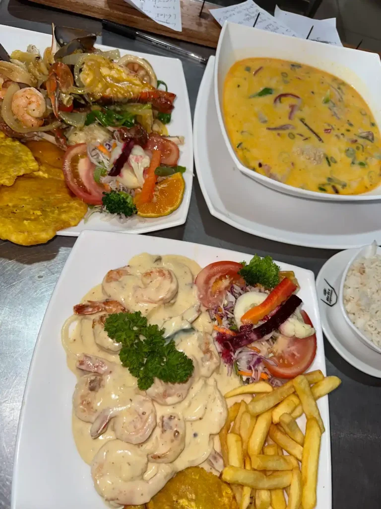 Platillos de mariscos, incluyendo camarones en salsa, pescado en crema y sopa de mariscos con acompañamientos.