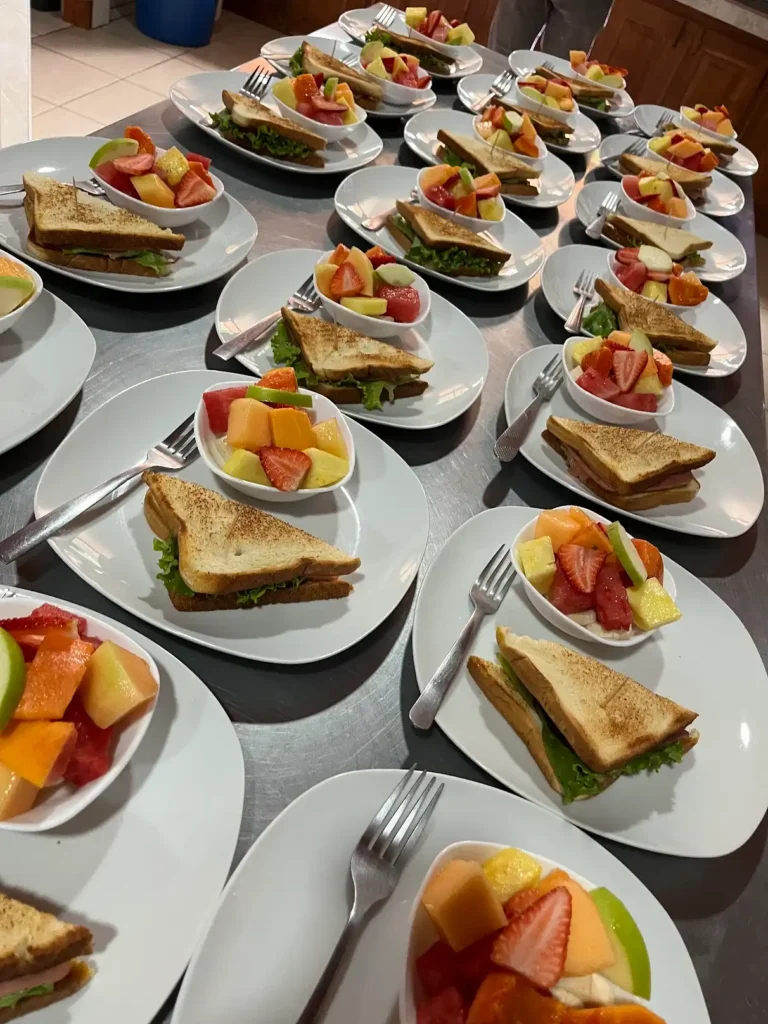 Platos servidos con sándwich tostado y tazón de fruta fresca, listos para un servicio de comida o evento.