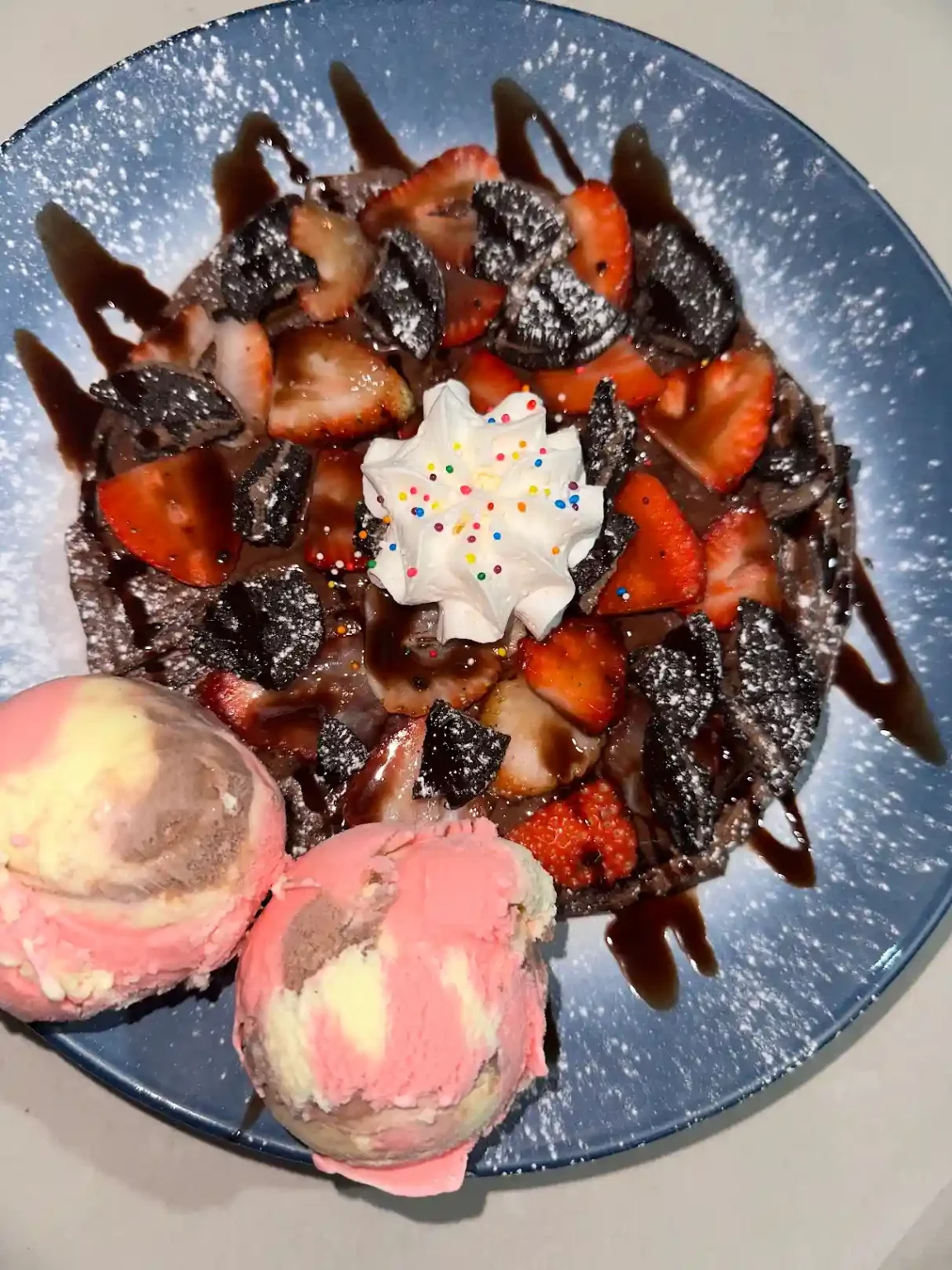 Waffle con fresas, chocolate, galleta y bolas de helado