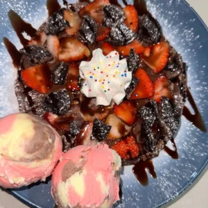 Waffle con fresas, chocolate, galleta y bolas de helado